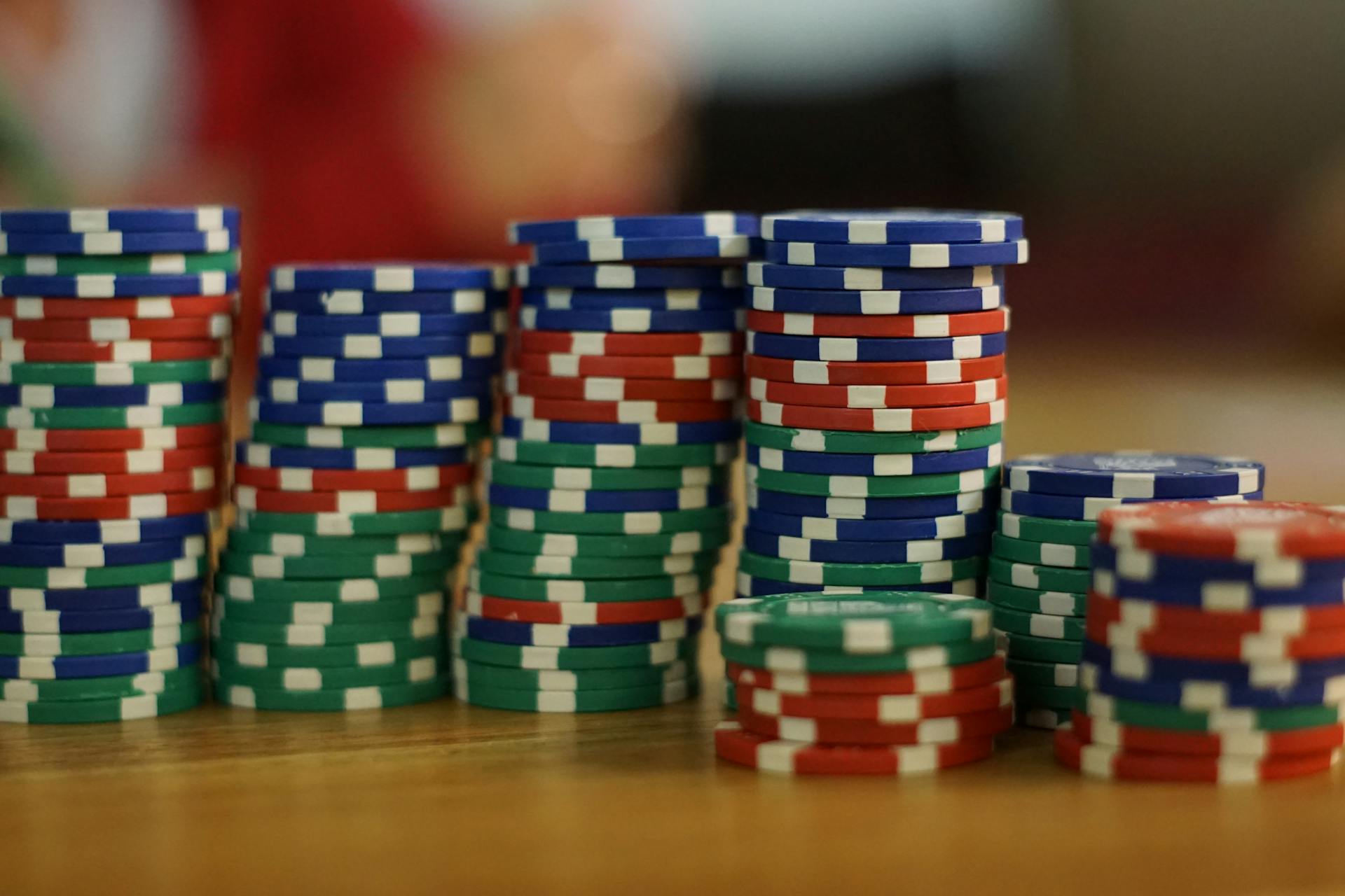 A close-up view of colorful stacked poker chips on a wooden table, perfect for casino themes.