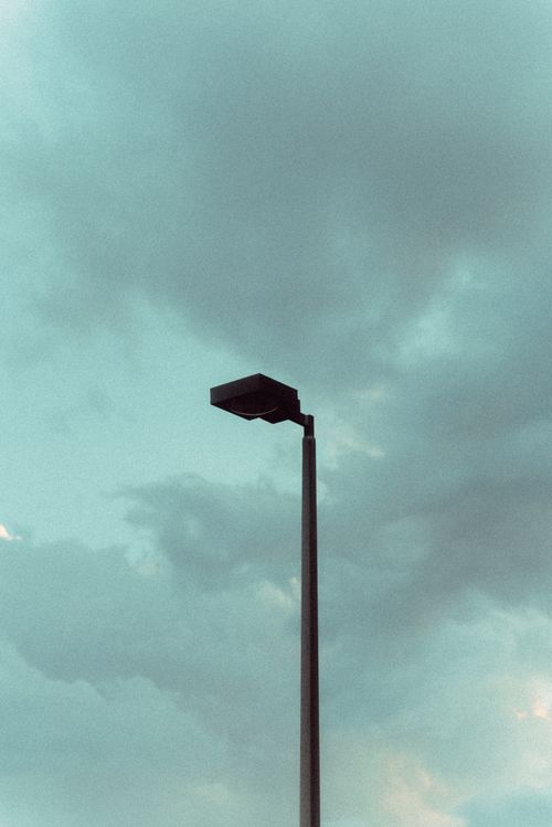 Free A low angle shot of a solitary street lamp set against a dramatic cloudy sky. Stock Photo