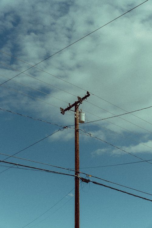Free A utility pole with power lines against a blue sky, showcasing energy infrastructure. Stock Photo
