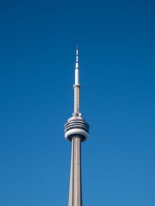 Free Striking view of Toronto's CN Tower reaching into a clear blue sky, a symbol of urban architecture. Stock Photo