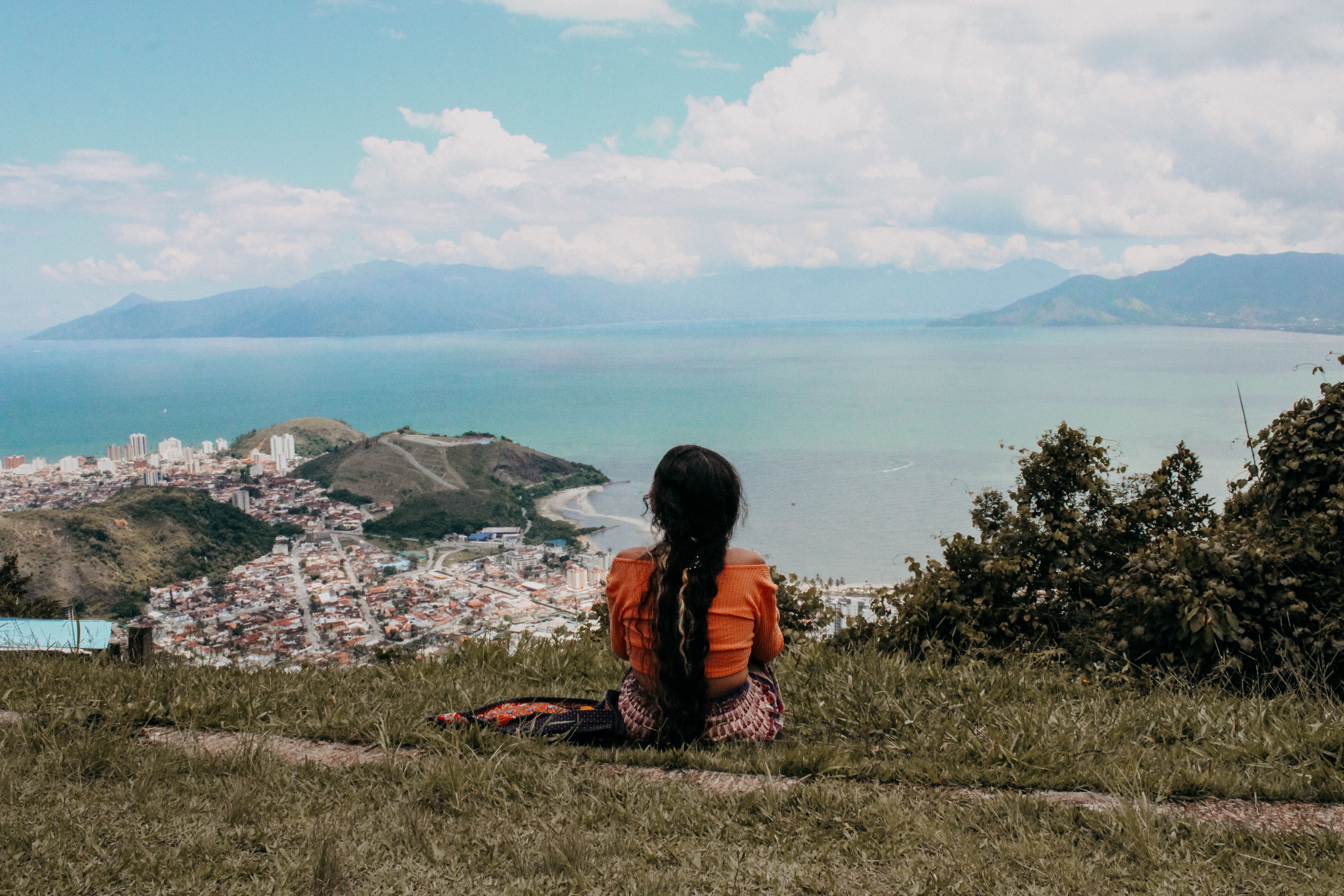 A woman with long hair enjoys the scenic ocean and city view from a hilltop in Paraty, Brazil.