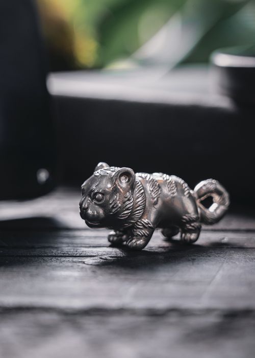Free Captivating close-up shot of a silver tiger figurine on a textured wooden background, ideal for decoration and design uses. Stock Photo
