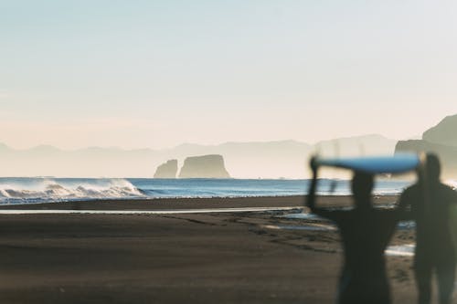 海岸近くでサーフボードを持っている人のシルエット