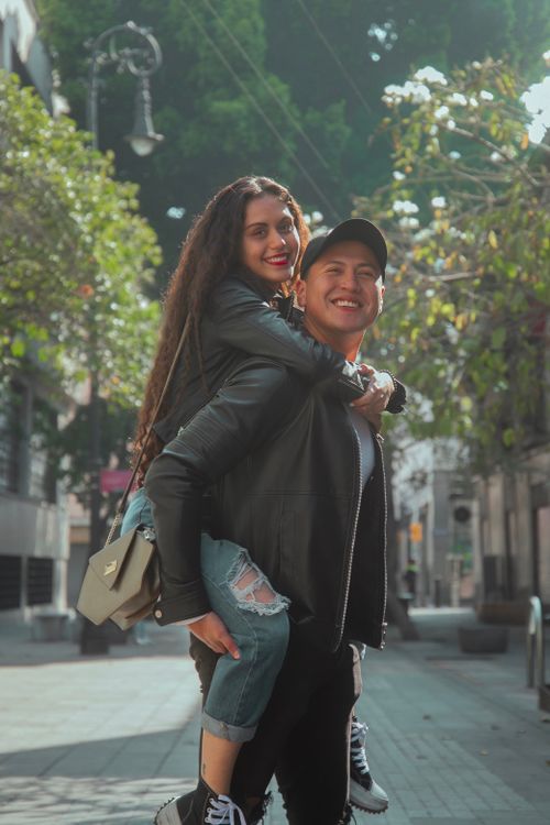 Free Happy couple enjoying a playful moment in a sunny urban environment. Stock Photo