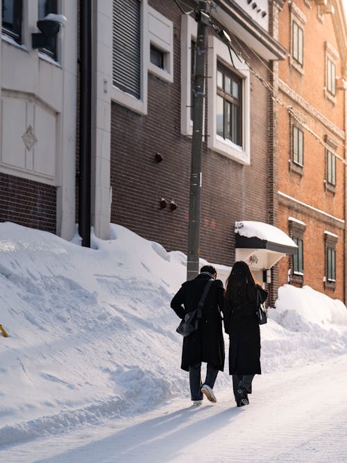 Woman and Man Walking on Street in Snow