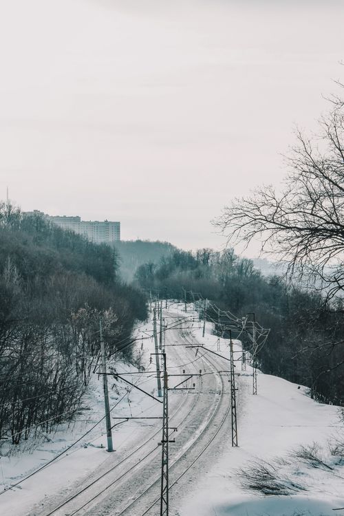 Free A peaceful winter railway scene overlooking snowy trees and hills under overcast skies. Stock Photo