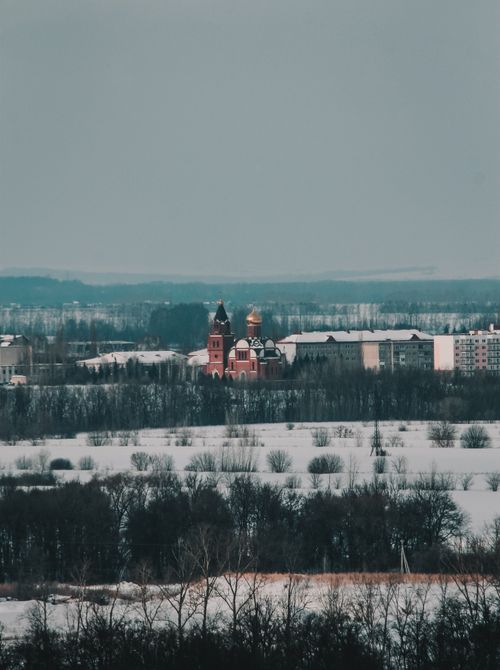 Free Aerial view of a snowy town featuring a remarkable red church amidst a winter landscape. Stock Photo