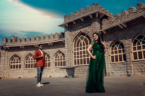Free Elegant couple posing in front of a medieval-style stone building exuding charm. Stock Photo