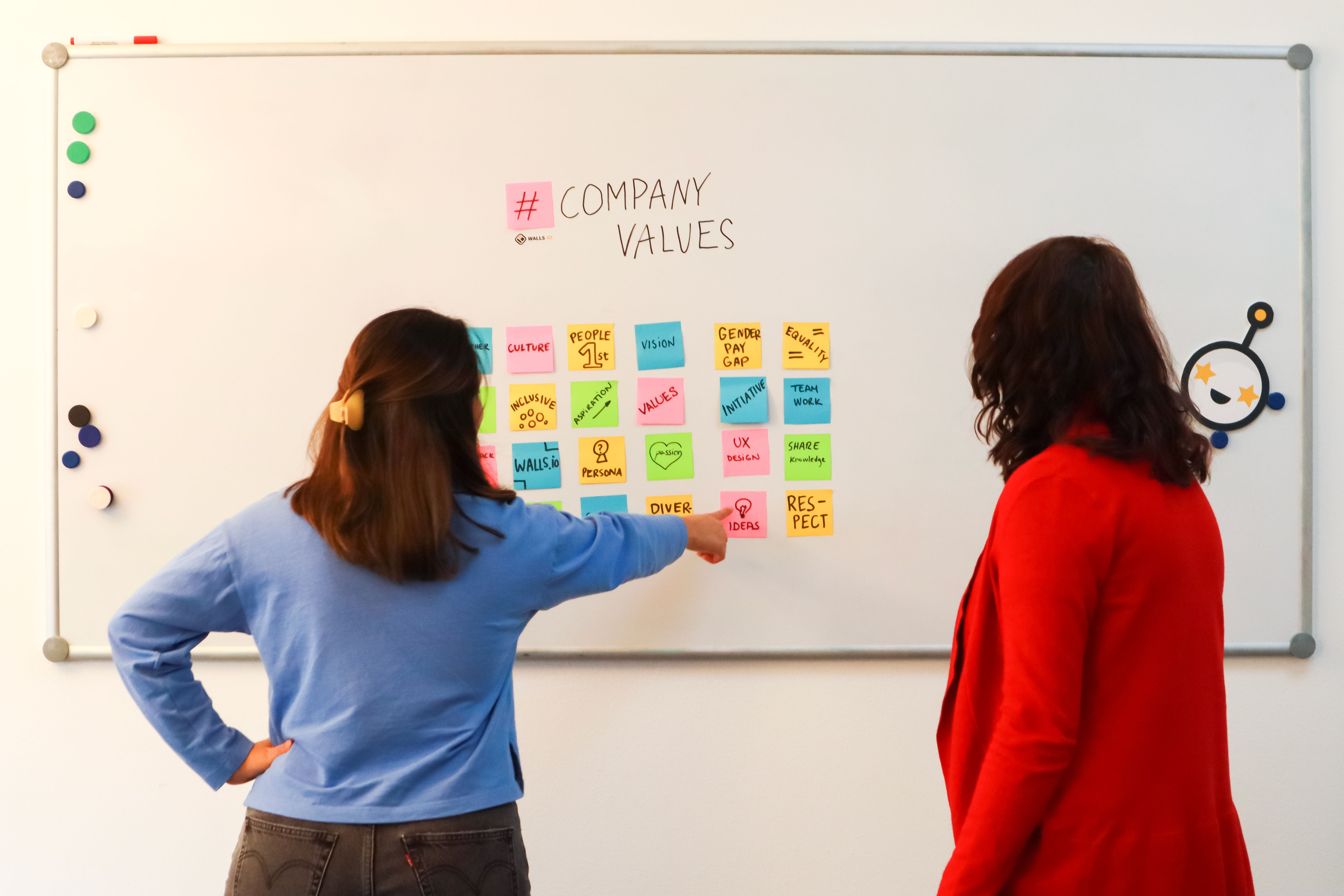 Employee Showing Sticky Note with Ideas on a Whiteboard with Company ...