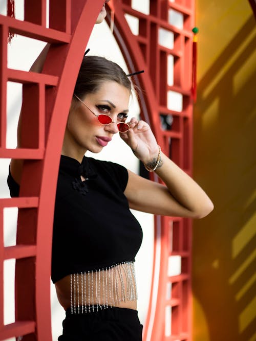Portrait of a Pretty Brunette Wearing Red Tinted Sunglasses and a Black Crop Top