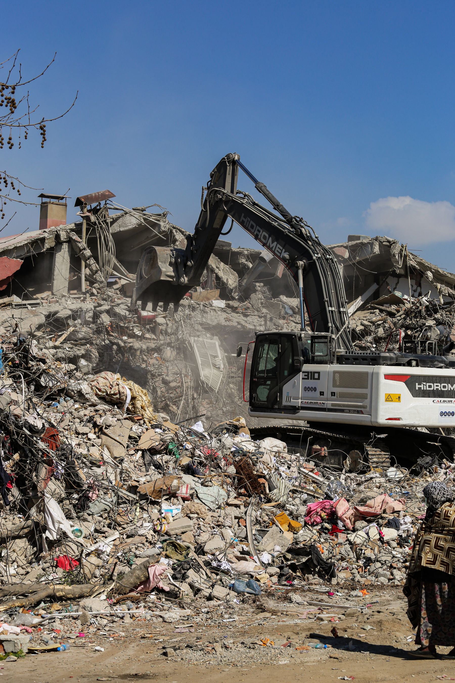 Excavator working among ruins and broken masonry after demolition