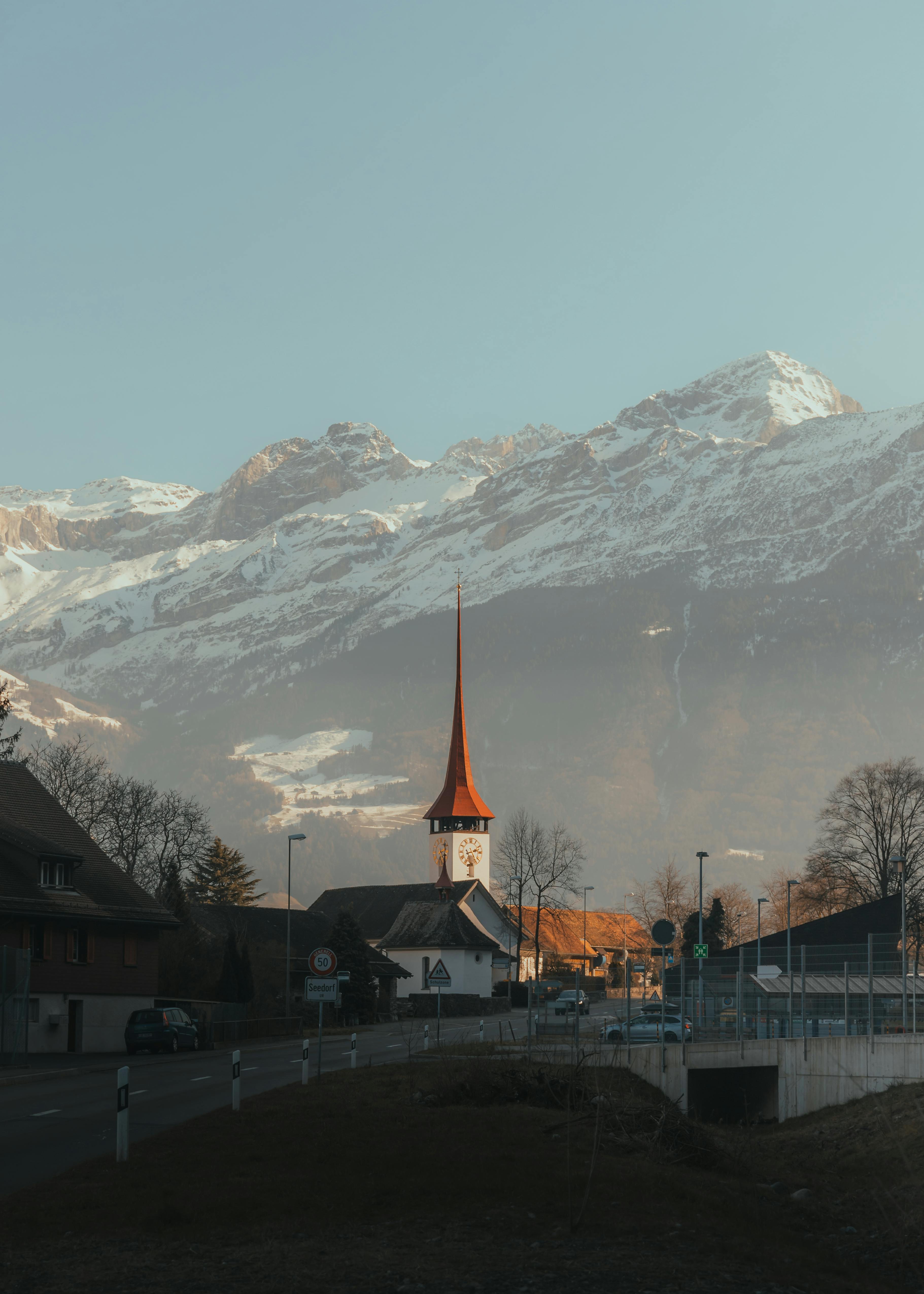 Scenic view of a Swiss village church amidst snowcapped mountains, showcasing winter elegance.