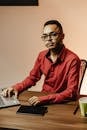 Man in Red Shirt by Table with Laptop