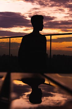 Silhouette of a teenager with city skyline at sunset, reflecting vivid colors and shapes.