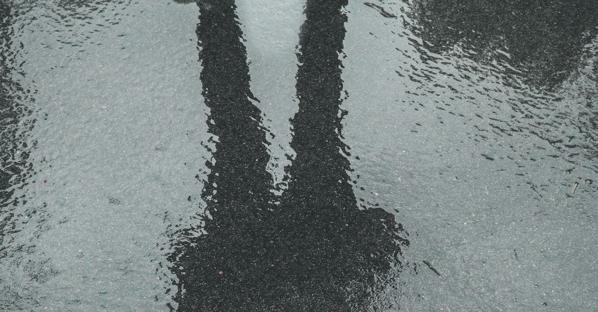 Rüyada Kendi Yansımasını Kaybetmek - Rüya Tabiri ve Anlamı - Creative photo of sneakers with a human reflection on wet pavement, capturing mystery and creativity.