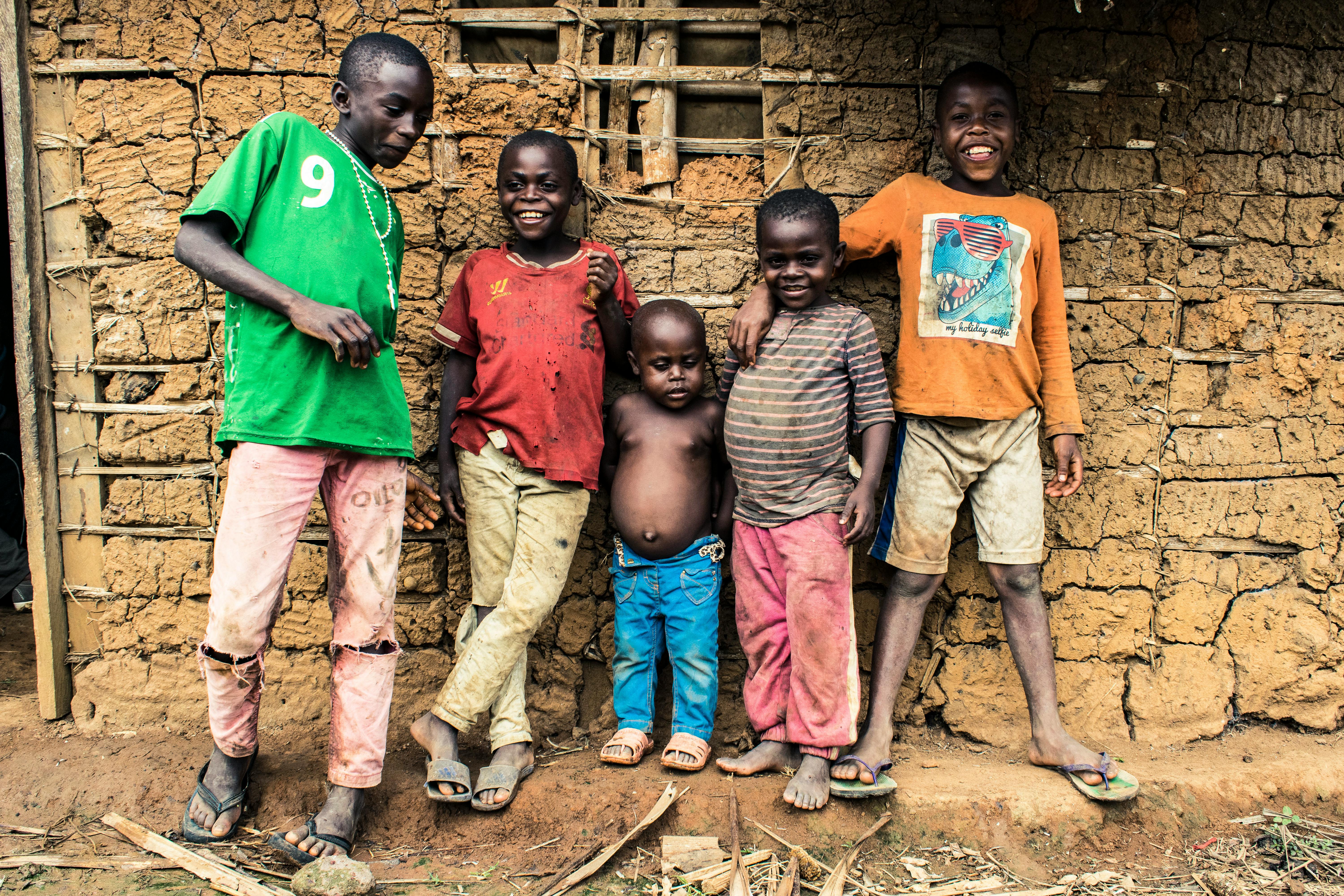 Group of smiling children standing in front of a rustic wall in Mintom, Cameroon.