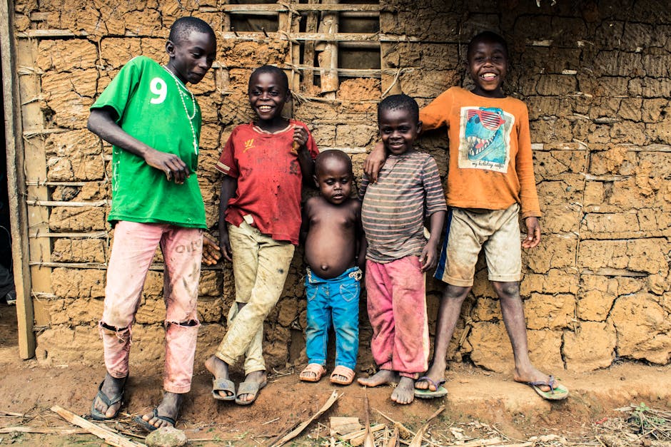 Group of smiling children standing in front of a rustic wall in Mintom, Cameroon.