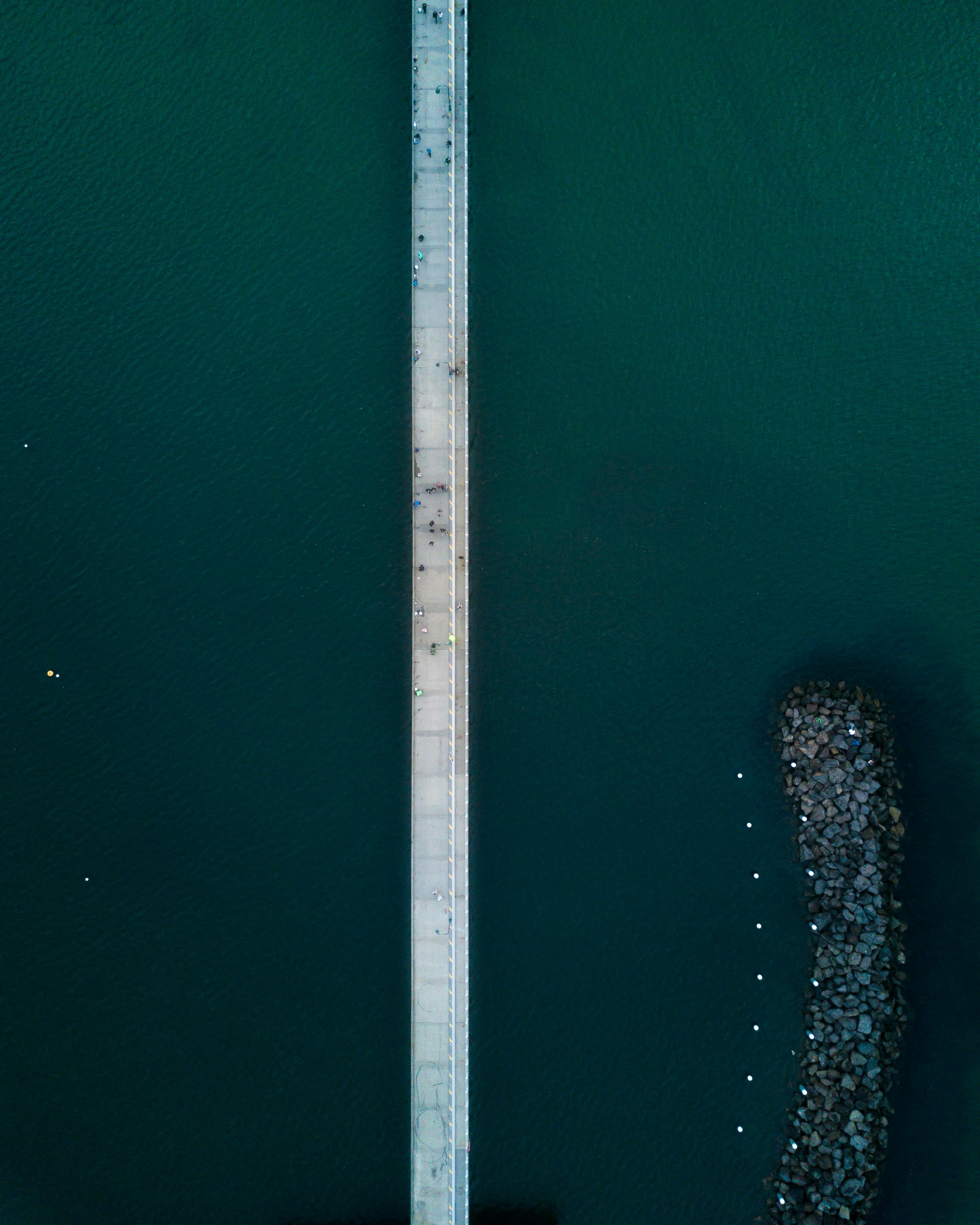 圣基尔达码头的鸟瞰图中，可见笔直的人行道延伸于水面之上，岩石清晰可见