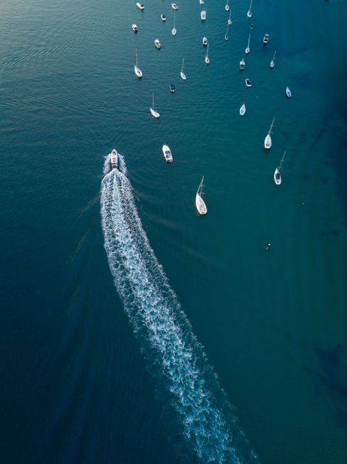 Explore the stunning aerial view of motorboats and sailboats on Sydney Harbor's turquoise waters.
