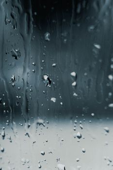 Macro shot of water droplets on a window creating a serene and moody atmosphere.
