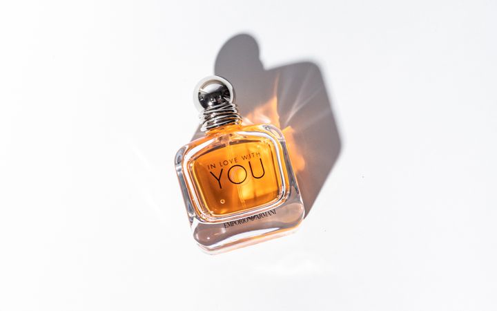 Minimalist photograph of a perfume bottle casting a shadow against a white background.