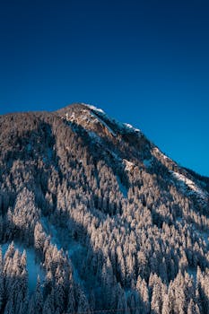 Snow-covered mountain landscape in Mayrhofen, Tirol, showcasing a pristine winter scene under a clear blue sky.