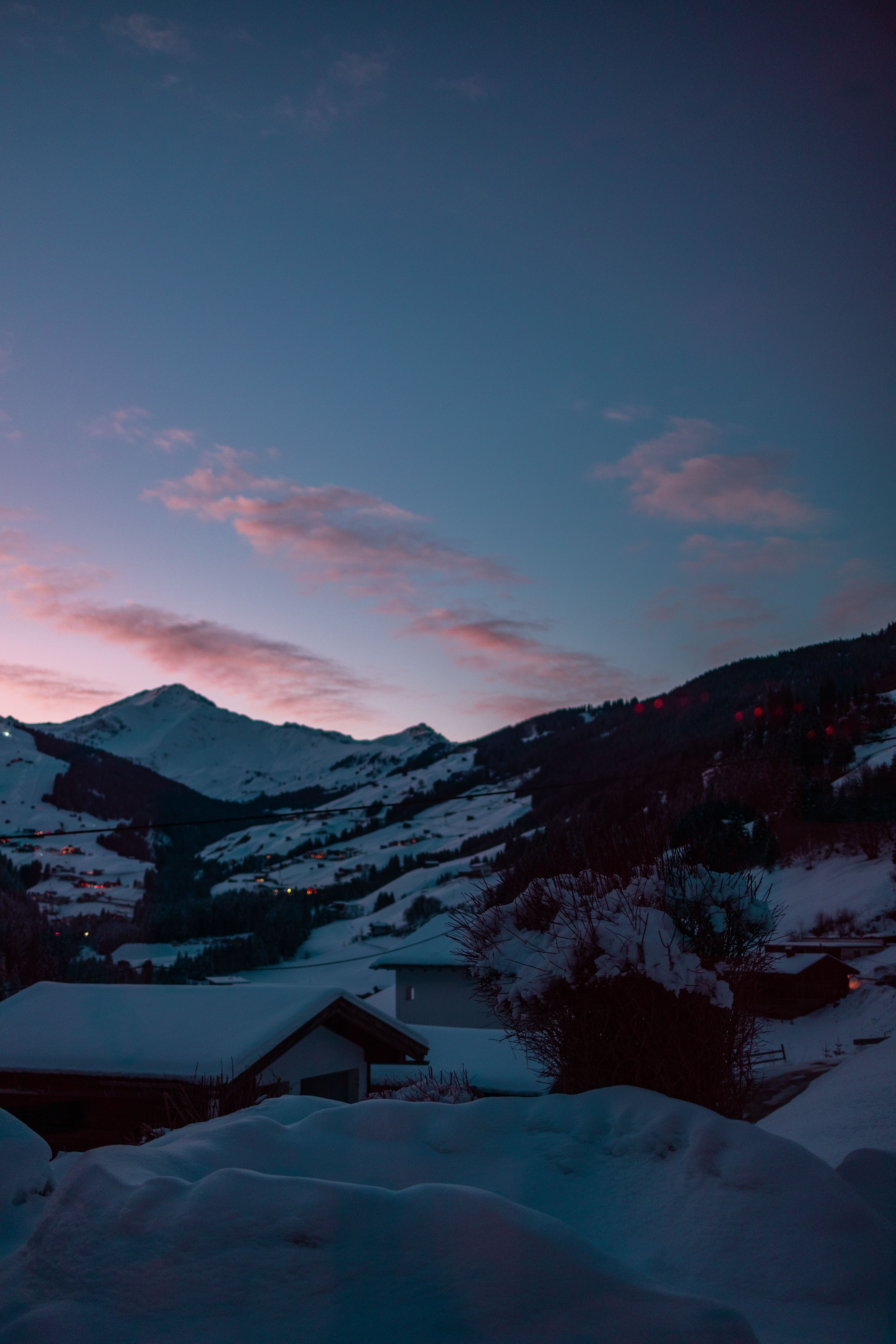 A sunset over a snowy mountain range with a mountain in the background ...