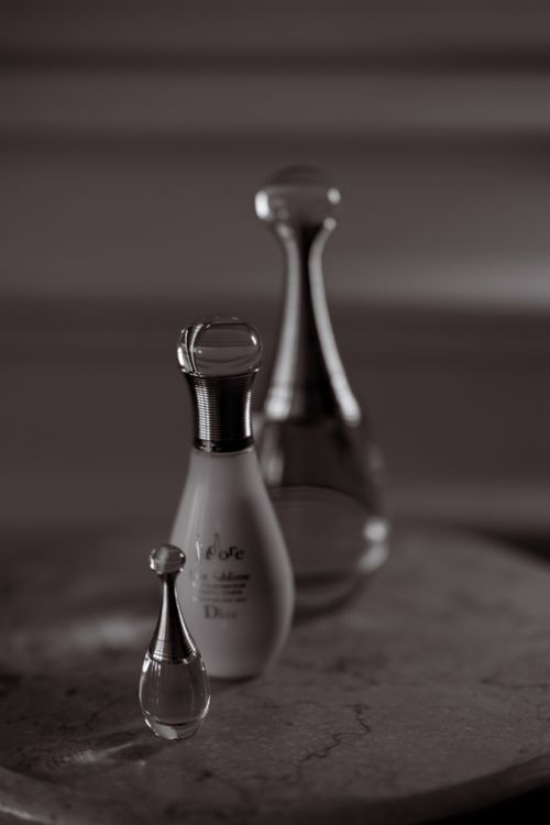 Free Grayscale image of elegant perfume bottles arranged vertically on a marble surface. Stock Photo