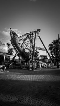Grayscale image of a ship ride at an amusement park, capturing dramatic swings.