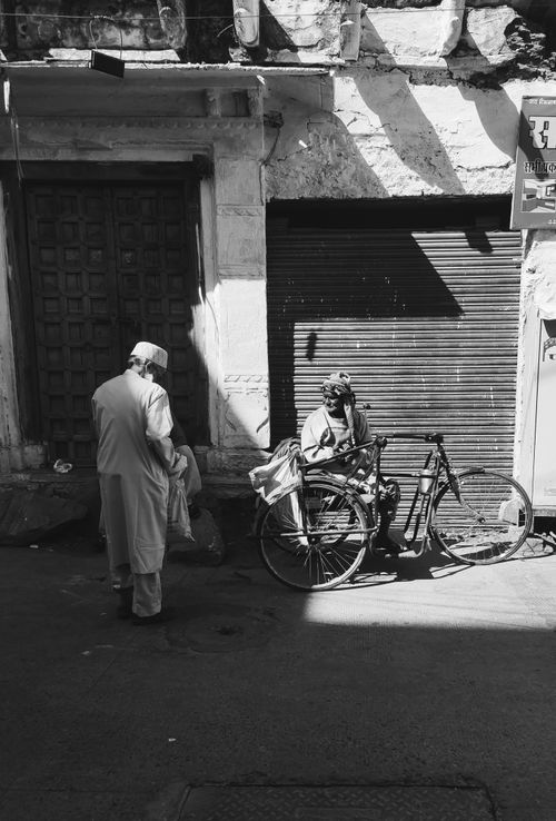 Free Black and white photo of elderly men with a bicycle in an urban street setting, highlighting daily life. Stock Photo