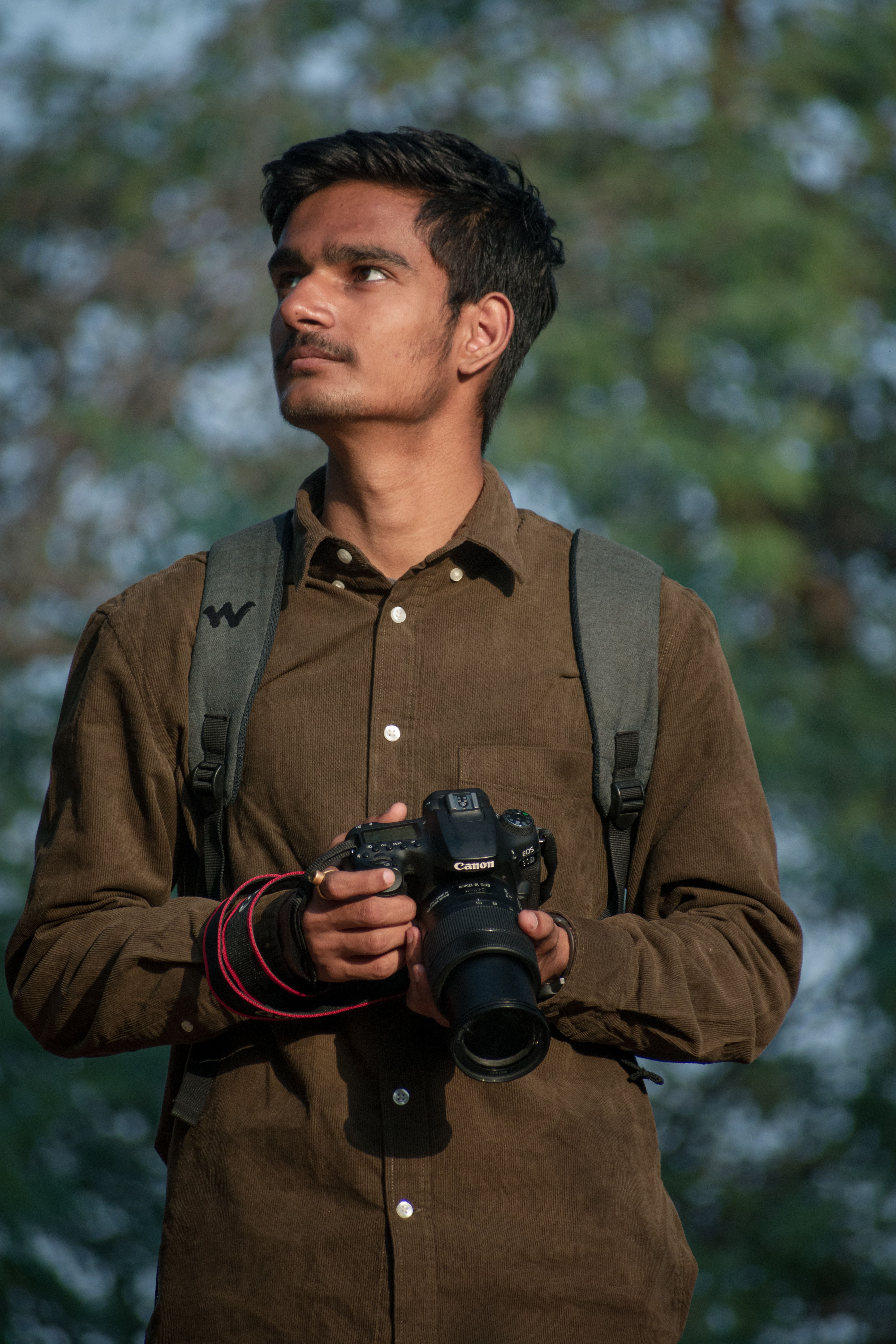 A young male photographer with a DSLR in nature, capturing creative outdoor shots.