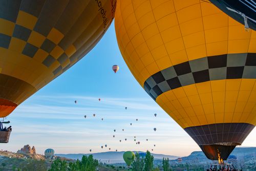 Free Vibrant hot air balloons soar over the Cappadocia landscape during sunrise, creating a mesmerizing view. Stock Photo