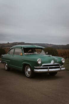 A vintage green car parked amidst a scenic Portland, OR backdrop, reflecting classic automotive charm.