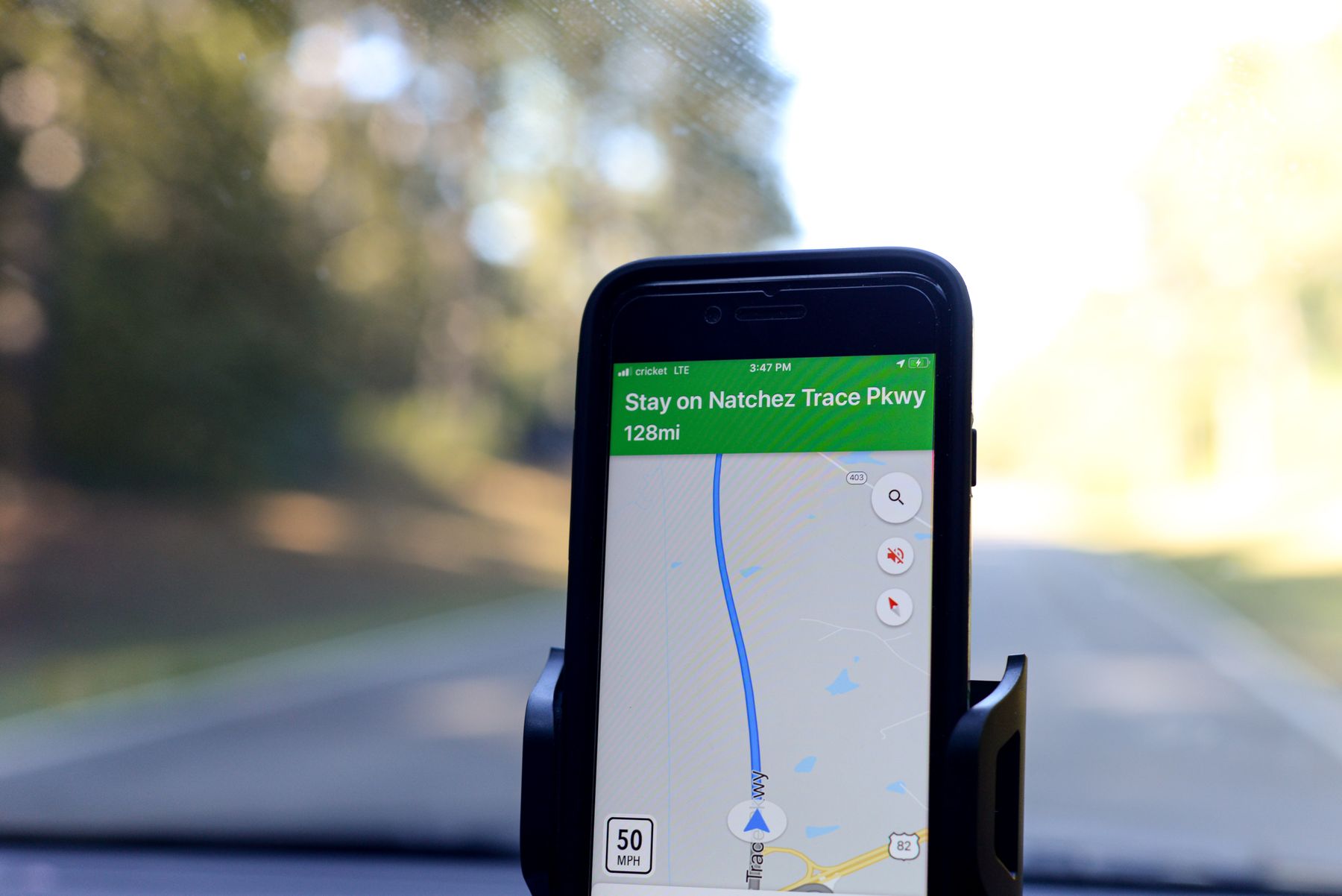 Smartphone displaying GPS navigation and a live route inside a vehicle