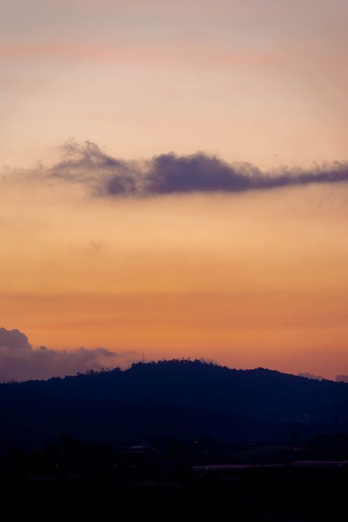 Free A breathtaking view of silhouetted hills under a vibrant yellow sky at sunset. Stock Photo