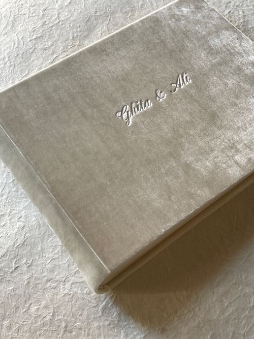 Free A luxurious velvet-covered wedding album resting on a textured surface, showcasing personalized embroidery. Stock Photo