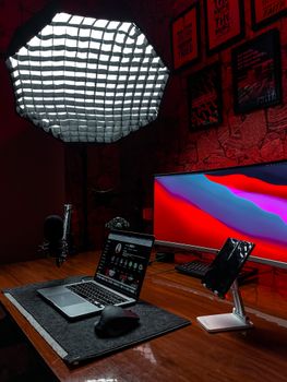 Illuminated desk with a laptop, monitor, and professional lighting setup in a modern home office.