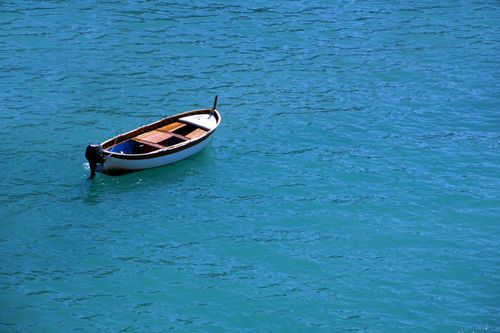 Free A lone wooden boat floats on calm, vibrant blue waters, evoking tranquility. Stock Photo