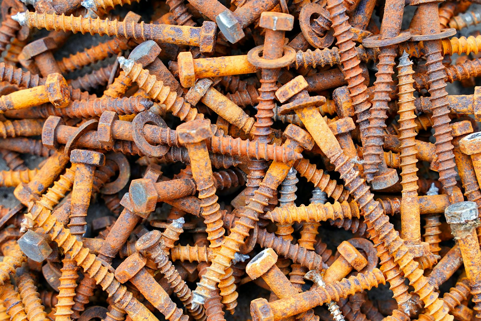 Detailed image showing a heap of rusty screws and bolts, capturing textures and colors.