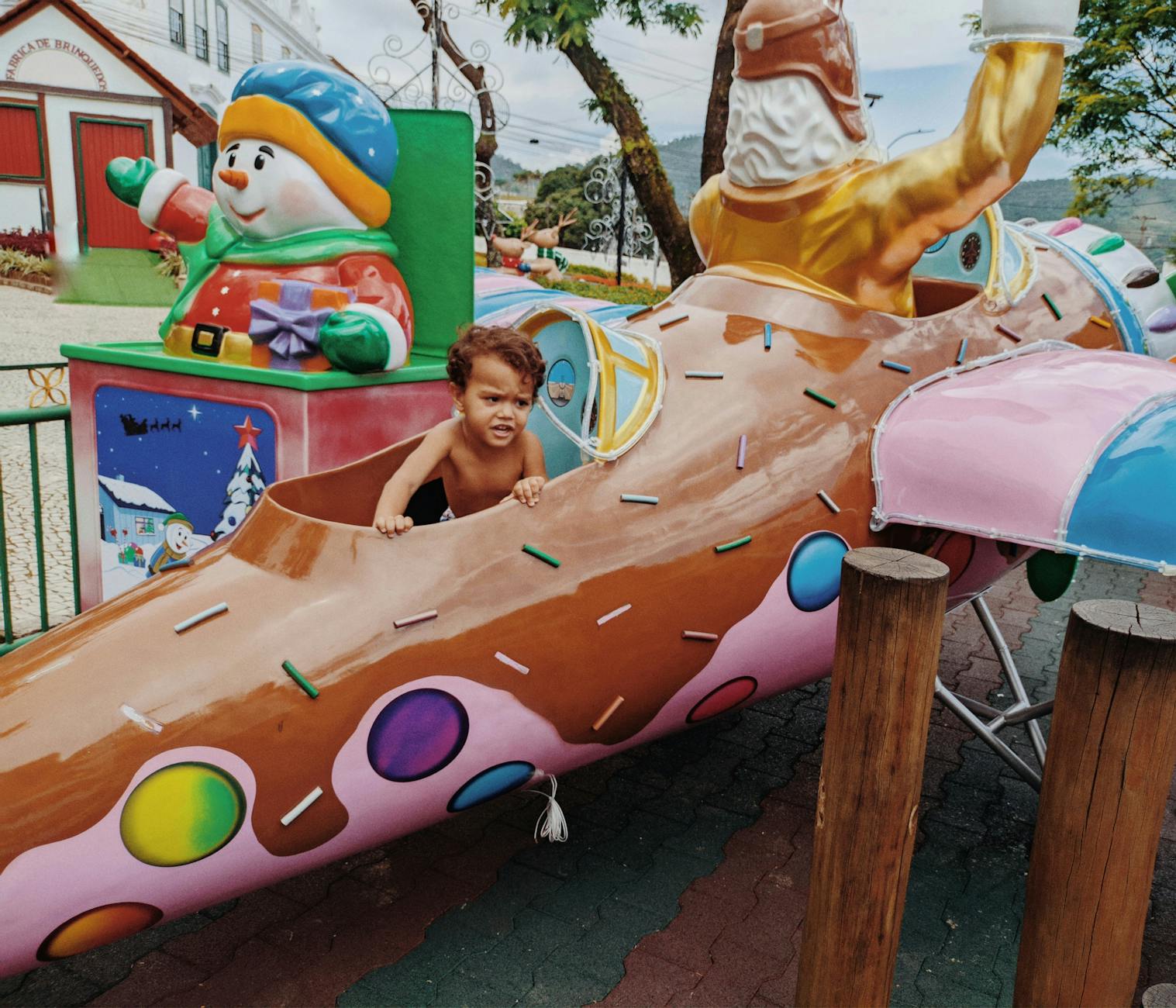 A child is sitting on a toy train at a park