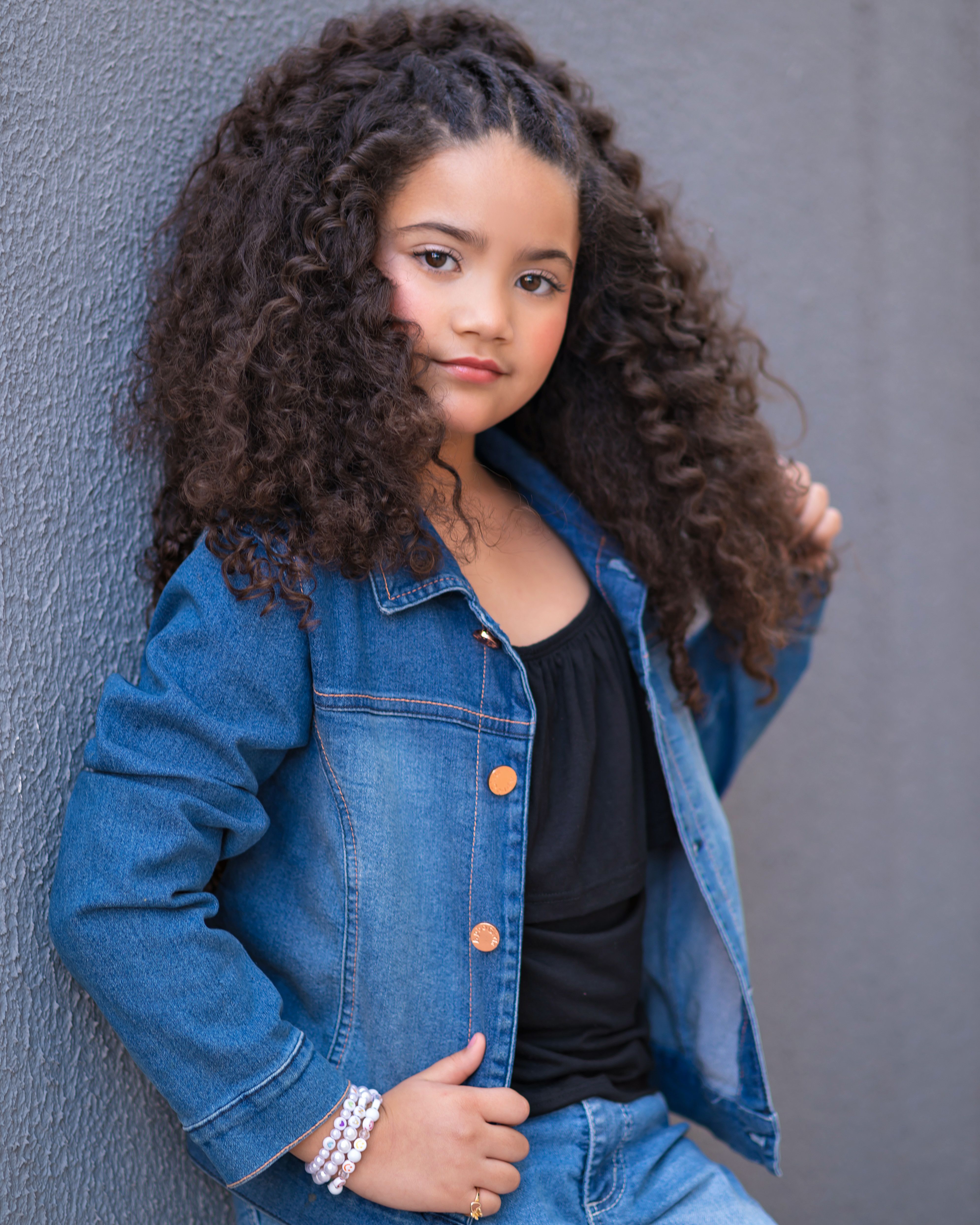 Stylish young girl in a denim jacket shows confidence and fashion flair.