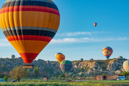 Free A vibrant scene of multiple hot air balloons flying over rocky terrain under a clear blue sky. Stock Photo