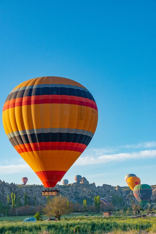 Free Colorful hot air balloons floating over a picturesque landscape under a clear blue sky. Stock Photo