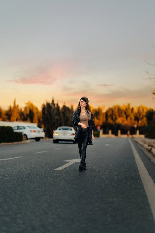 Woman Walking on an Asphalt Street at Sunset