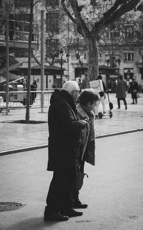 Free Black and white photo of an elderly couple walking in a city street in Valencia, Spain. Stock Photo
