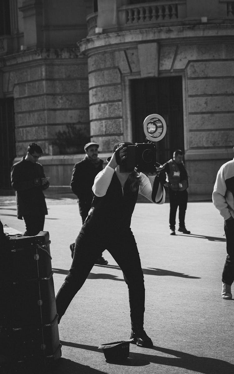 Black And White Photo Of A Photographer With A Retro Camera And A Group Of Men