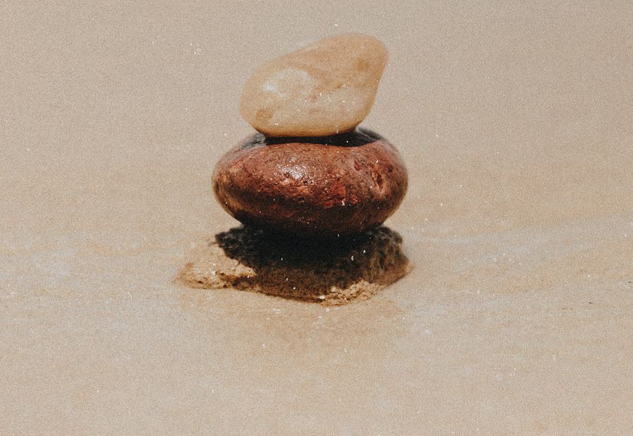 Two smooth stones balanced on sand