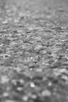 Close-up of a textured concrete surface in grayscale, showcasing detailed patterns and selective focus.
