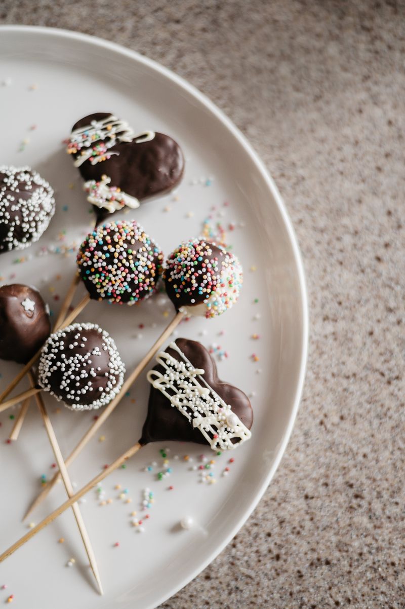 Chocolate cake pops with sprinkles on a white plate