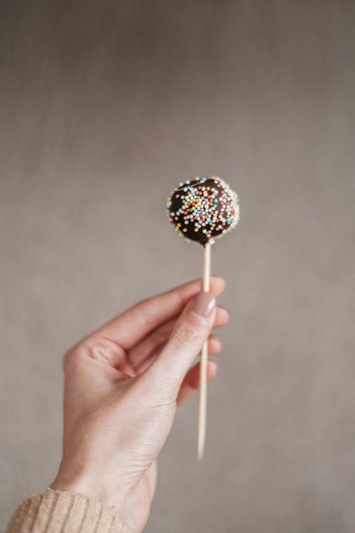 Hand Holding a Chocolate Round Lollipop